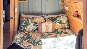 Ein gemütliches Zimmer mit einem Bett, das mit floralem Bettzeug ausgestattet ist, einem an der Wand befestigten Regal mit Kerzen und einem Schild mit der Aufschrift 'Süße Träume'.