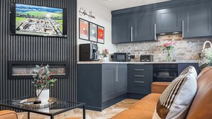 Une cuisine moderne avec des meubles de couleur sombre, une machine à café et un grille-pain.