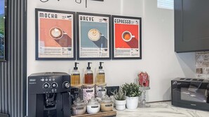 Un café-bar équipé d’une machine à expresso Magneica, de tasses à café étiquetées et d’un four à micro-ondes Goodmans.