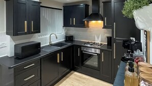 A modern kitchen with dark cabinetry, a stainless steel sink, and a built-in oven. - 2 bedroom accommodation in Newcastle Upon Tyne (Newcastle Upon Tyne)