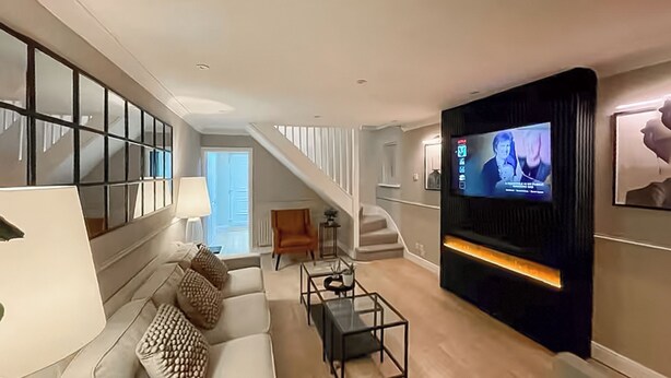 A modern living room with a sofa, coffee table, and a television mounted on the wall. - 2 bedroom accommodation in Newcastle Upon Tyne (Newcastle Upon Tyne)