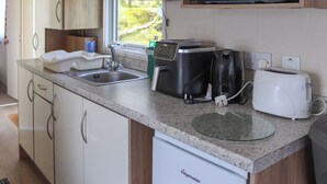 Une cuisine compacte équipée d’un four à micro-ondes, d’un grille-pain, d’une machine à café et d’un lave-vaisselle.