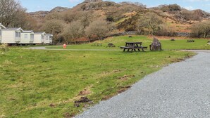 En campingplats med picknickbord, en grusgång och en rad med husvagnar.