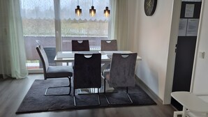 A modern dining area with a table, chairs, and pendant lights.