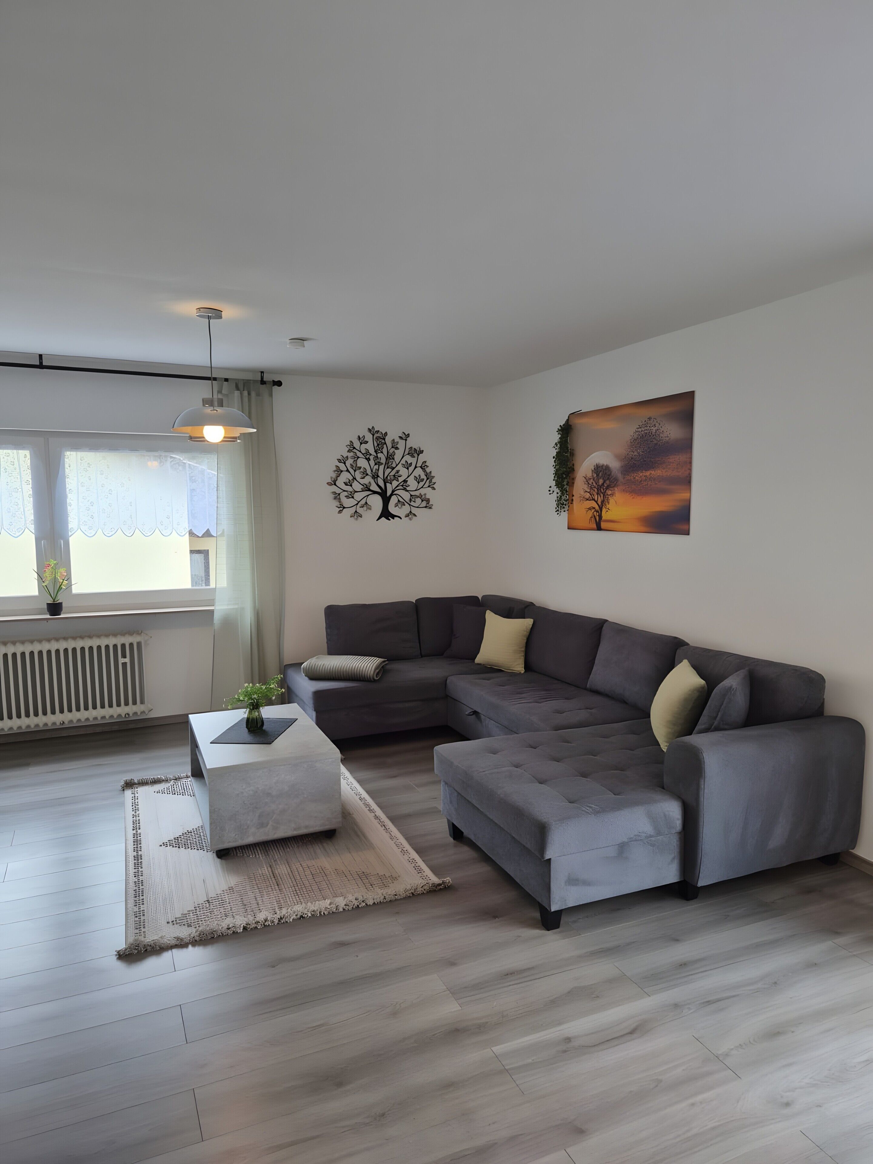 A modern living room with a sectional sofa, a coffee table, and a painting on the wall.