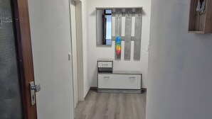 A hallway with a wooden door, a mirror, a coat rack, and a small cabinet.