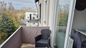A balcony with wicker furniture, a table, and a view of the surrounding area.