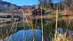 A cabin by a lake with reflections, surrounded by trees and hills. - Chalet des Briseux (Saint-Maurice-sur-Moselle)