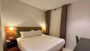 Quarto de hotel com cama, abajures, mesa de cabeceira, mesa e cadeira.