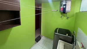 A bathroom with green walls, a toilet, a sink, and a water heater mounted on the wall.
