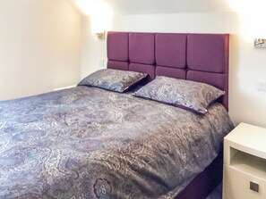 Ein Bett mit einem gemusterten Überwurf, einem Kopfteil und zwei Kissen.