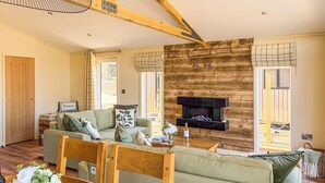 Un salón amplio con chimenea, vigas de madera y un sofá.