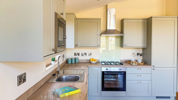 Una cocina moderna con horno empotrado, pileta de acero inoxidable y una pequeña isla con estufa a gas.