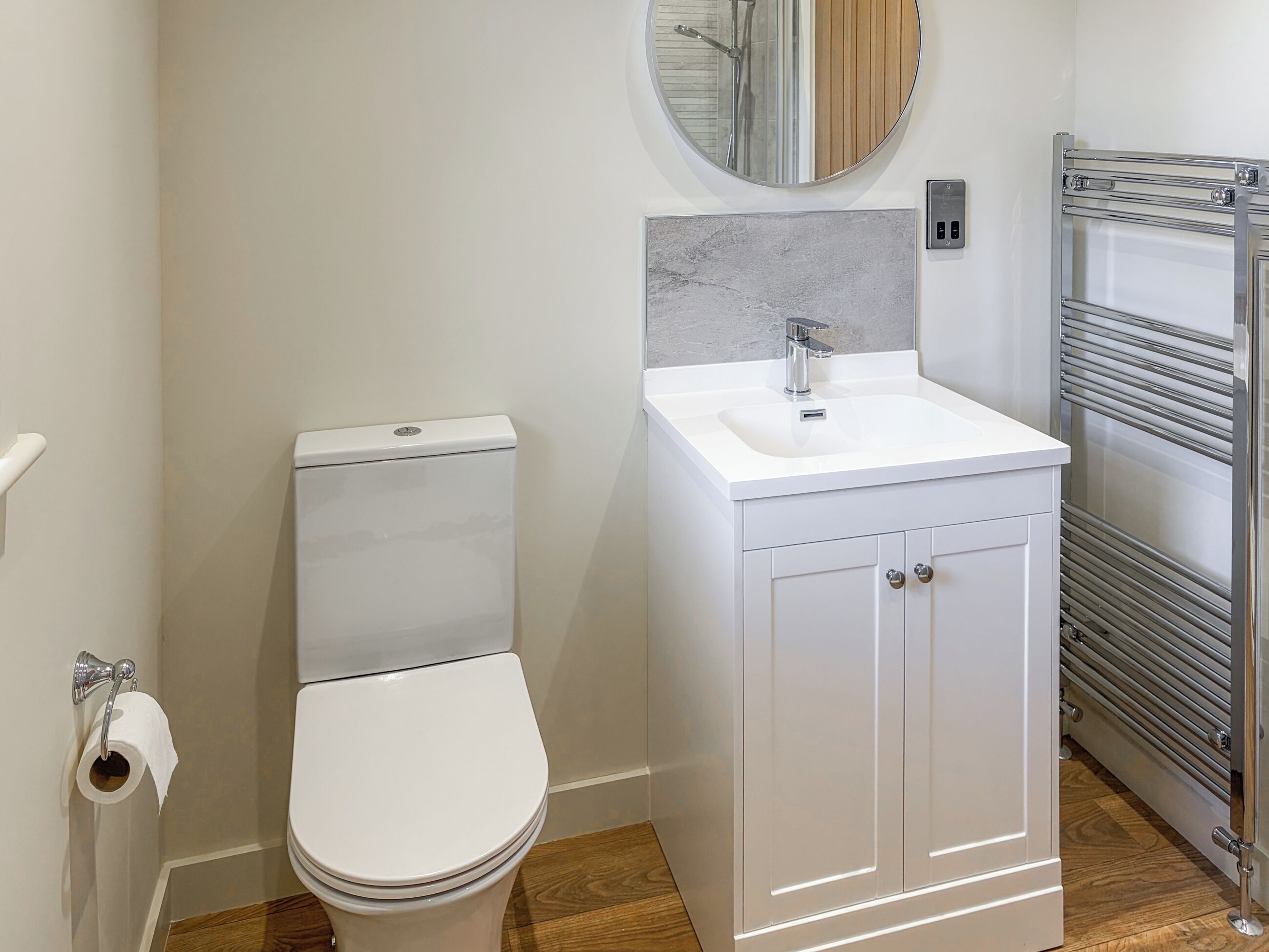 Ein modernes Badezimmer mit Toilette, Waschbecken, Spiegel und Handtuchhalter.