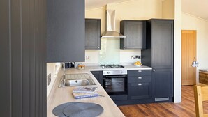 Una cocina moderna con armarios oscuros, una estufa a gas y un lavamanos.