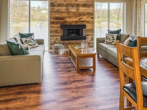 A living room with a fireplace, sofas, a coffee table, and a view of a lake.
