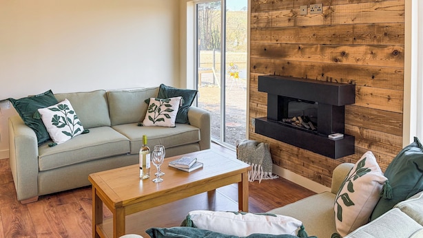 Un salon avec un canapé, une table basse, une cheminée et une vue par la fenêtre.