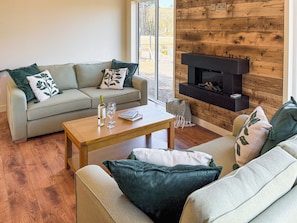 A living room with a sofa, coffee table, fireplace, and a view through a window.