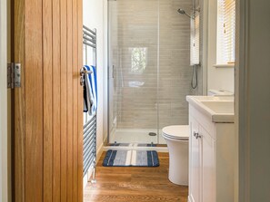 A bathroom with a glass shower enclosure, a toilet, a sink, and a wooden door. - 3 bedroom accommodation in Perranporth (Perranporth)