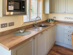 Una cocina con un microondas de acero inoxidable, un fregadero y armarios de madera.