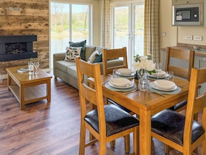 A dining area with a wooden table set for four, a sofa with cushions, and a fireplace.
