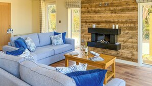 A modern living room with a sofa set, a coffee table, and a fireplace. - 3 bedroom accommodation in Perranporth (Perranporth)