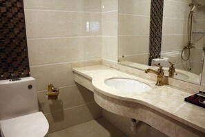 A bathroom with a toilet, sink, and shower.