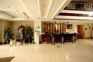 A lobby with a reception desk, a statue, and potted plants.