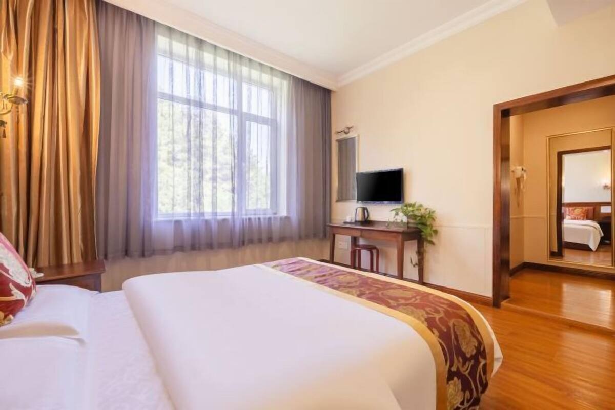 Habitació d'hotel amb un llit gran, una taula de treball i una televisió, i un mirall.