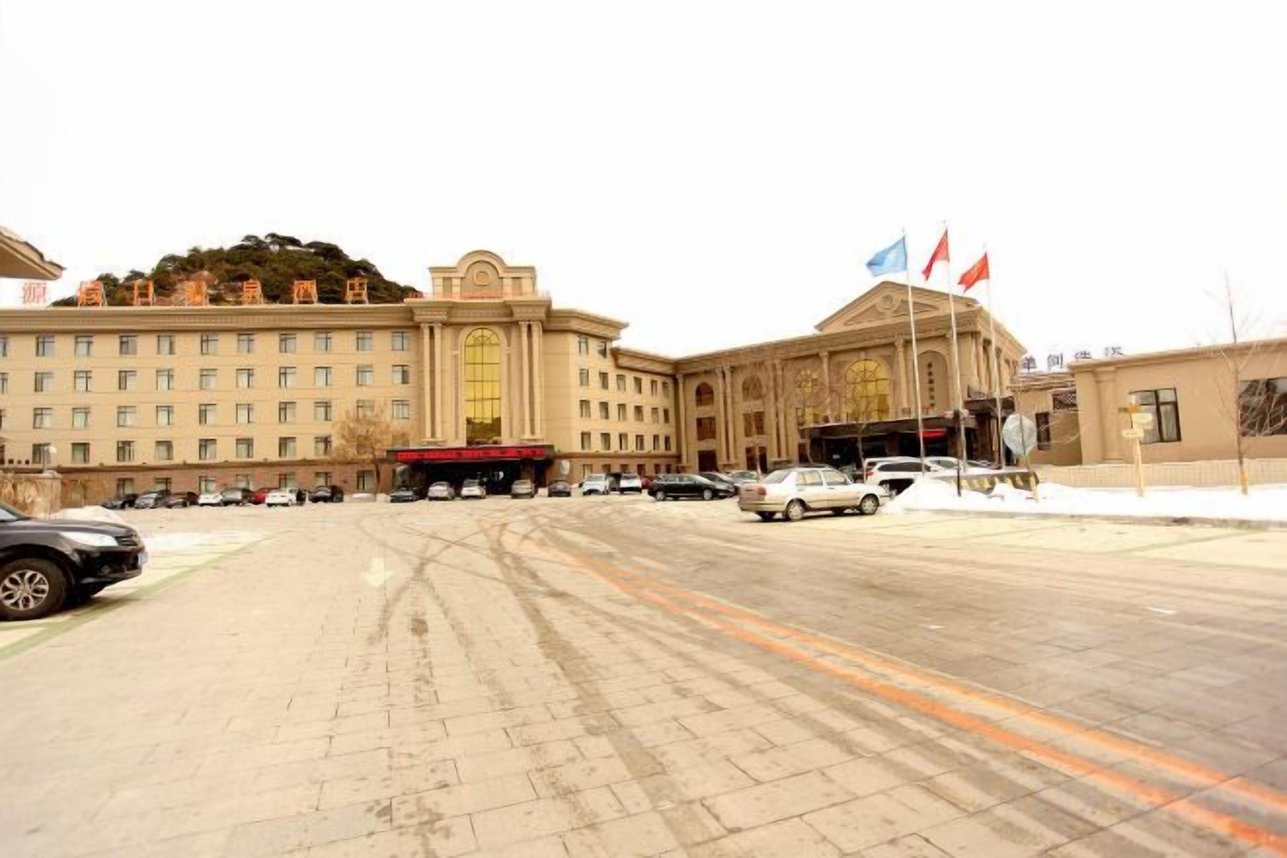 A large building with multiple floors, a central entrance, and several flags.
