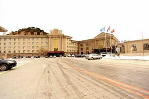 A large building with multiple floors, a central entrance, and several flags. - Longyuan Holiday Hot Spring Hotel (Anshan)