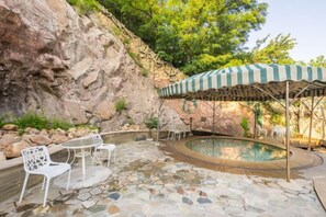 A pool area with a stone floor, white chairs, and a striped umbrella. - Longyuan Holiday Hot Spring Hotel (Anshan)