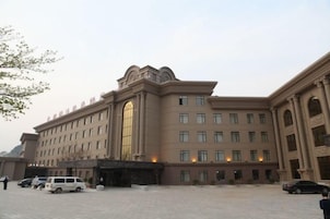 Un hotel grande de varios pisos con un patio central, múltiples accesos y un diseño arquitectónico clásico.