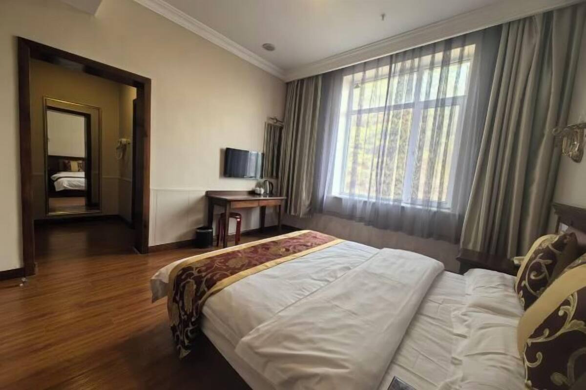 Habitació d'hotel amb un llit gran, una taula de treball, televisió i vista a l'exterior.