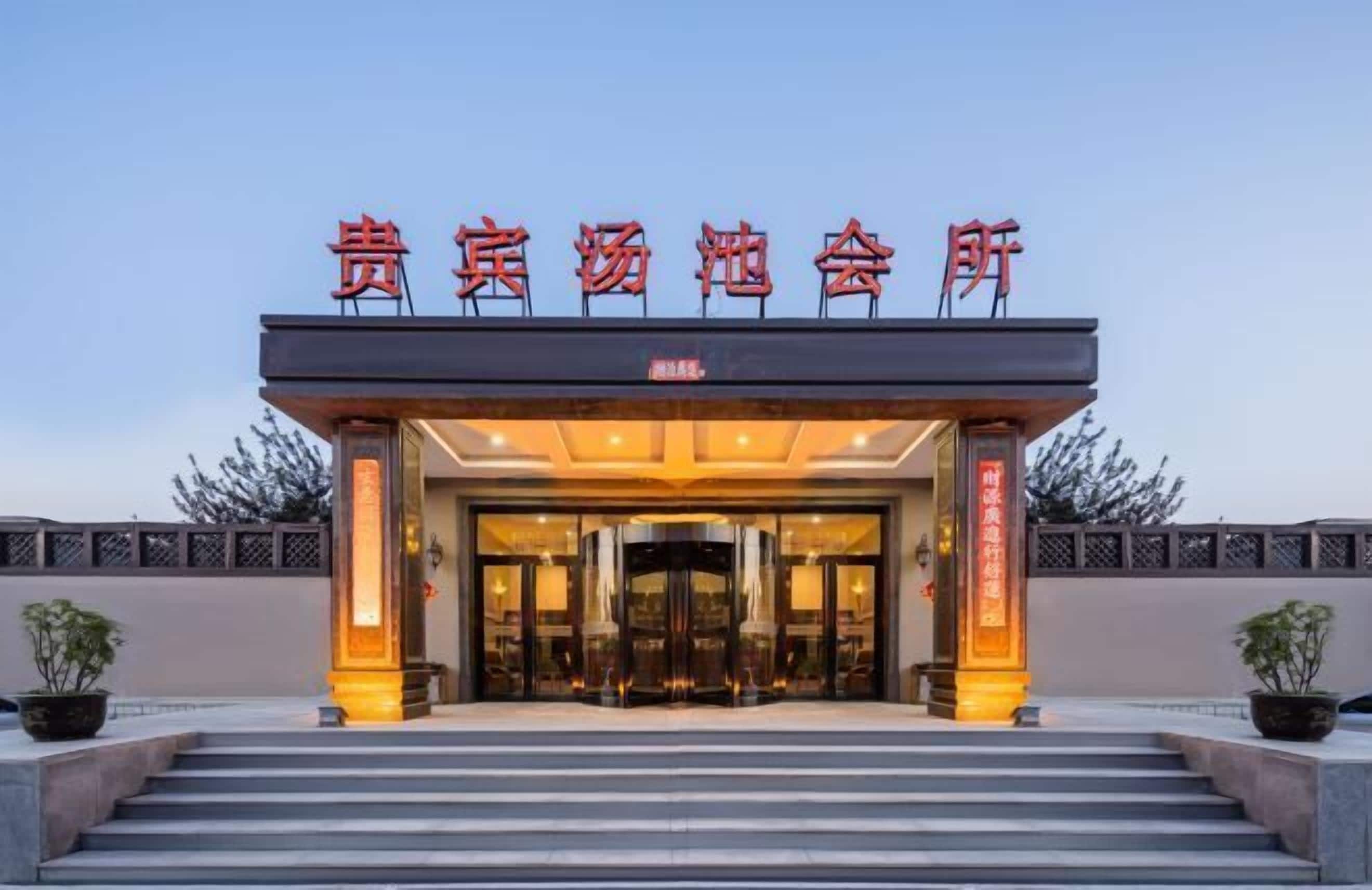 A hotel entrance with a large sign, steps leading up to it, and a well-lit facade.