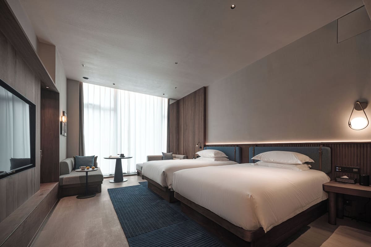 A modern hotel room with a large bed, a seating area with a table, and a TV.
