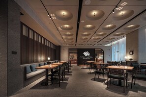 En modern hotellobby med en lång receptionsdisk, en sittgrupp och en stor vägg med hotellets namn.