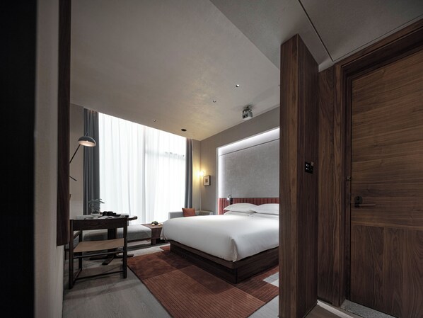 Una habitación de hotel con cama, escritorio, silla y un amplio armario de madera.