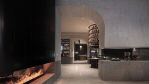 A modern interior with a curved bookshelf, a reception desk, and a fire feature. - Hangzhou Tipsy Hotel (Jinsha Lake) (Hangzhou)