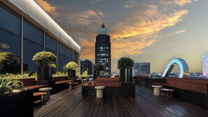 A rooftop terrace with seating, planters, and a city skyline view. - Hangzhou Tipsy Hotel (Jinsha Lake) (Hangzhou)
