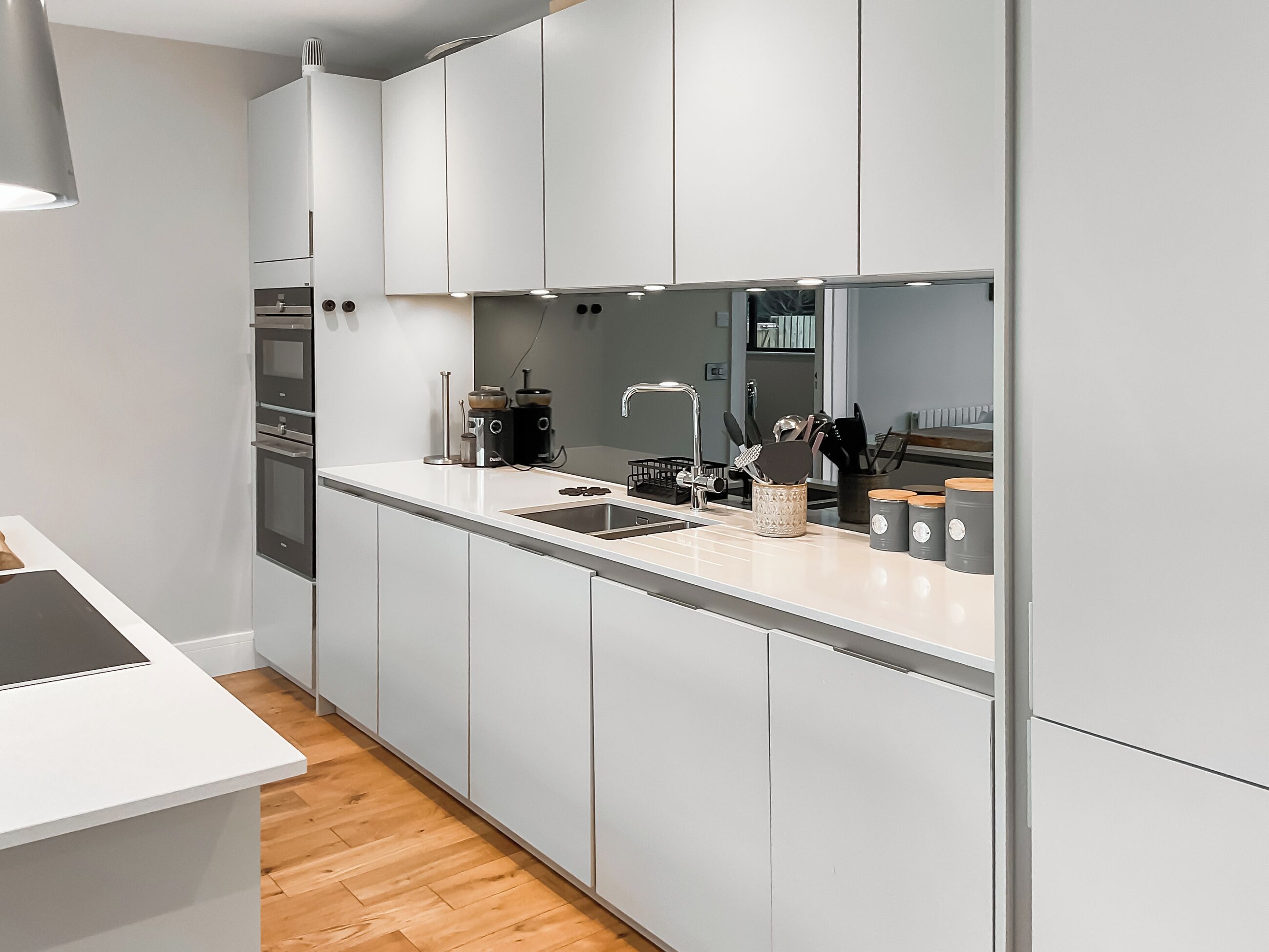 Een moderne keuken met witte kasten, een roestvrijstalen spoelbak en een inbouwoven.