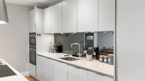 Een moderne keuken met witte kasten, een roestvrijstalen spoelbak en een inbouwoven.