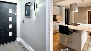 Een moderne keuken met een bar, een zwarte deur en een lichtgekleurde muur.