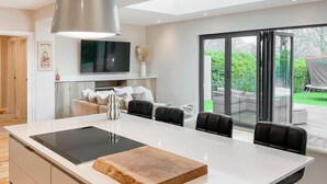 Een moderne keuken met een groot eiland, een flatscreen televisie en een schuifdeur naar het buitenterras.