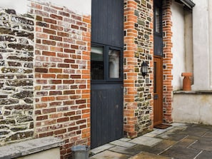 Un bâtiment en briques avec une porte sombre, une fenêtre et un mur en pierre.