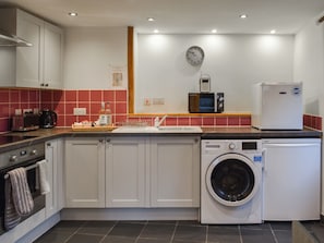 Une cuisine compacte équipée d’un lave-linge, d’un four à micro-ondes et d’un grille-pain.