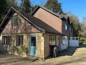 A two-story house with a stone facade, a blue door, and a covered grill area. - 3 bedroom accommodation in Near Bath (Bradford-on-Avon)