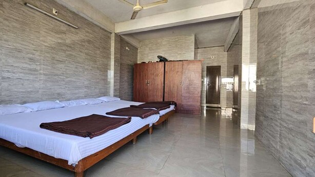 A modern hotel room with a large bed, a wardrobe, and a bathroom visible through an open door.