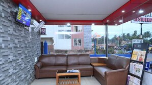 A seating area with a sofa and a table, a TV mounted on the wall, and a view of the outside.
