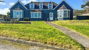 A two-story house with a front porch, a driveway, and a well-maintained lawn. - 5 bedroom accommodation in Perranporth (Perranporth)